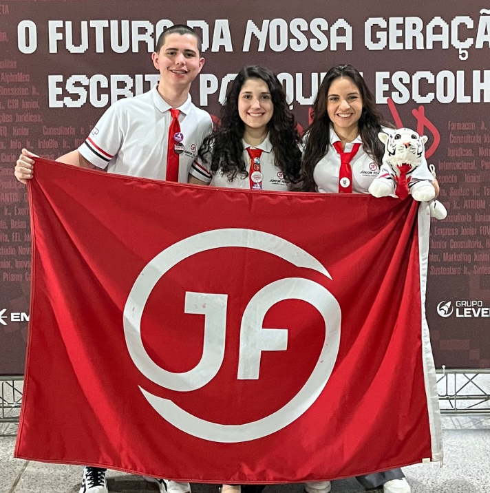 Equipe da Júnior FEA-RP reunida com a bandeira da empresa